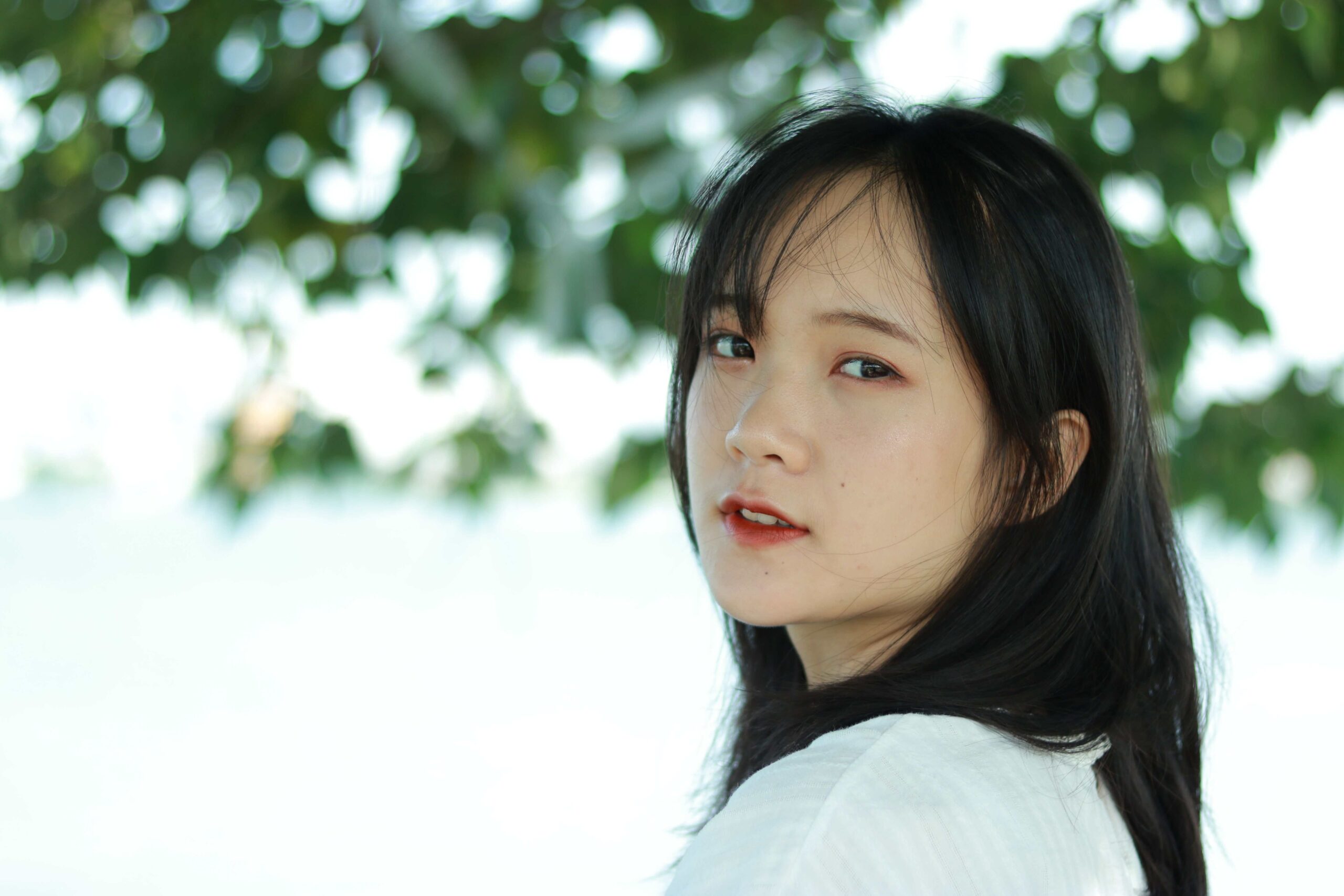 Close-up portrait of an east Asian woman with long black hair, standing outdoors.