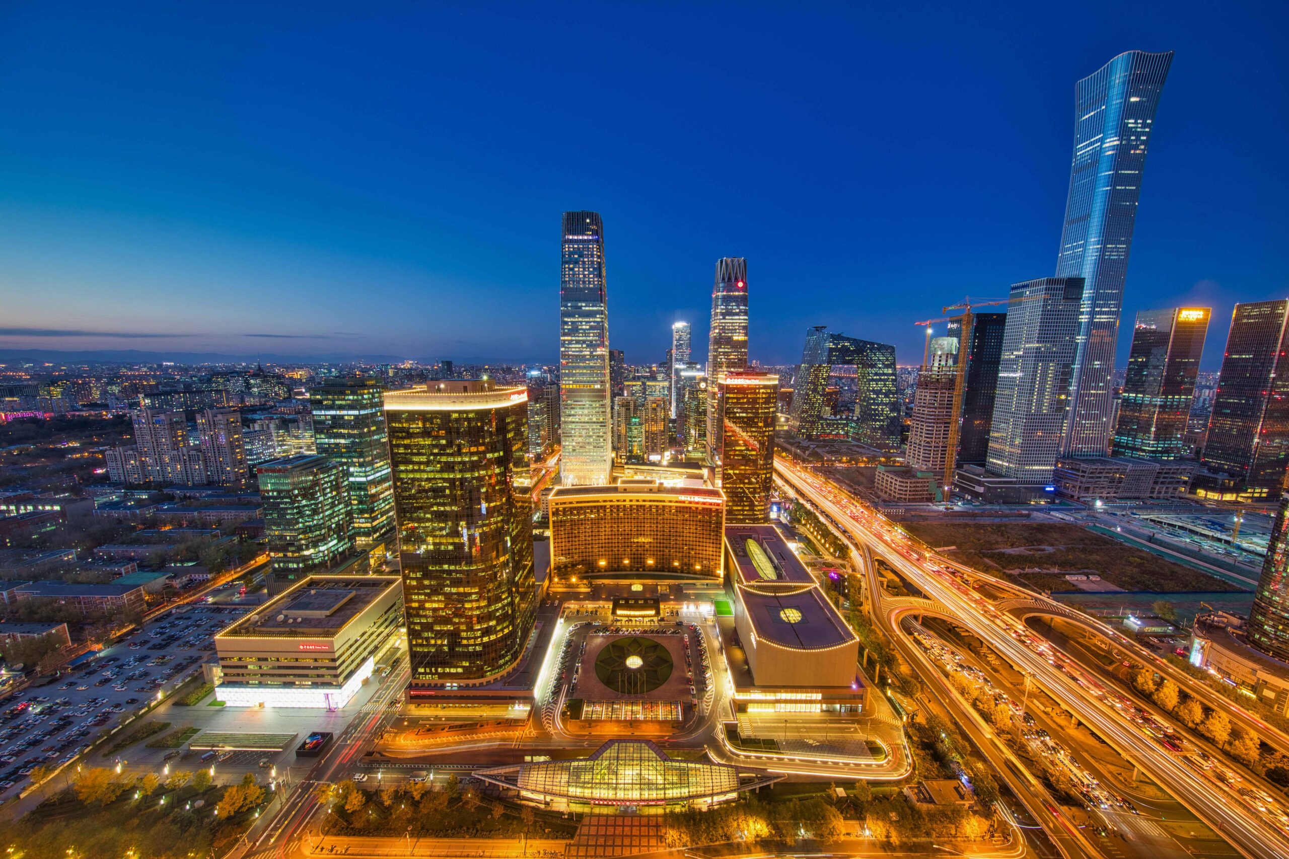 Stunning cityscape featuring skyscrapers and city lights at twilight with a clear blue sky.